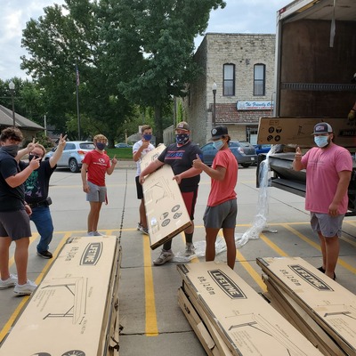 Wamego Football Players Helping Dana Bring In New Tables Before Hoo Haw