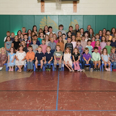 2025 All-School Photo in front of brand new gym mats adorned with our mascot, the Eagle.