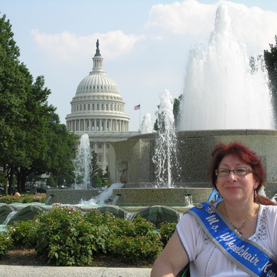 Female wheelchair user pictured in front of fountains with the US Capitol in the background
